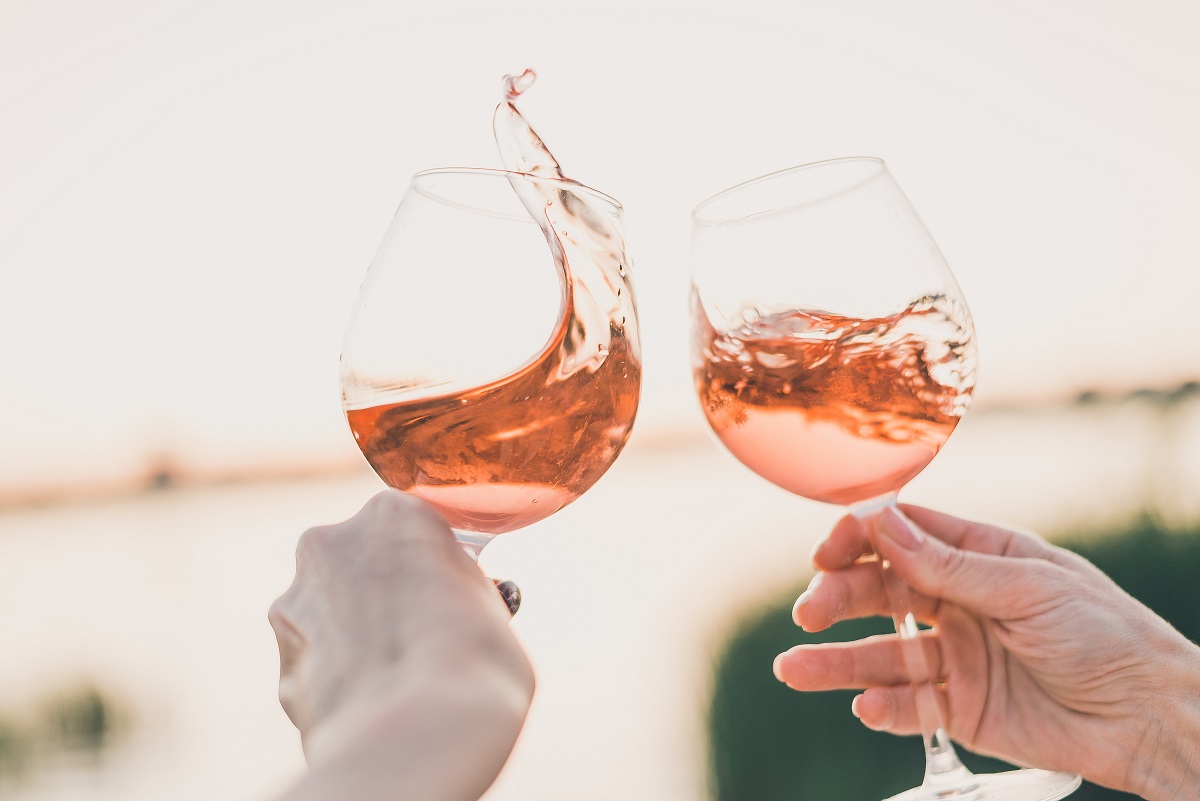 Two,Glasses,Of,Rose,Wine,In,Hands,Against,The,Sunset